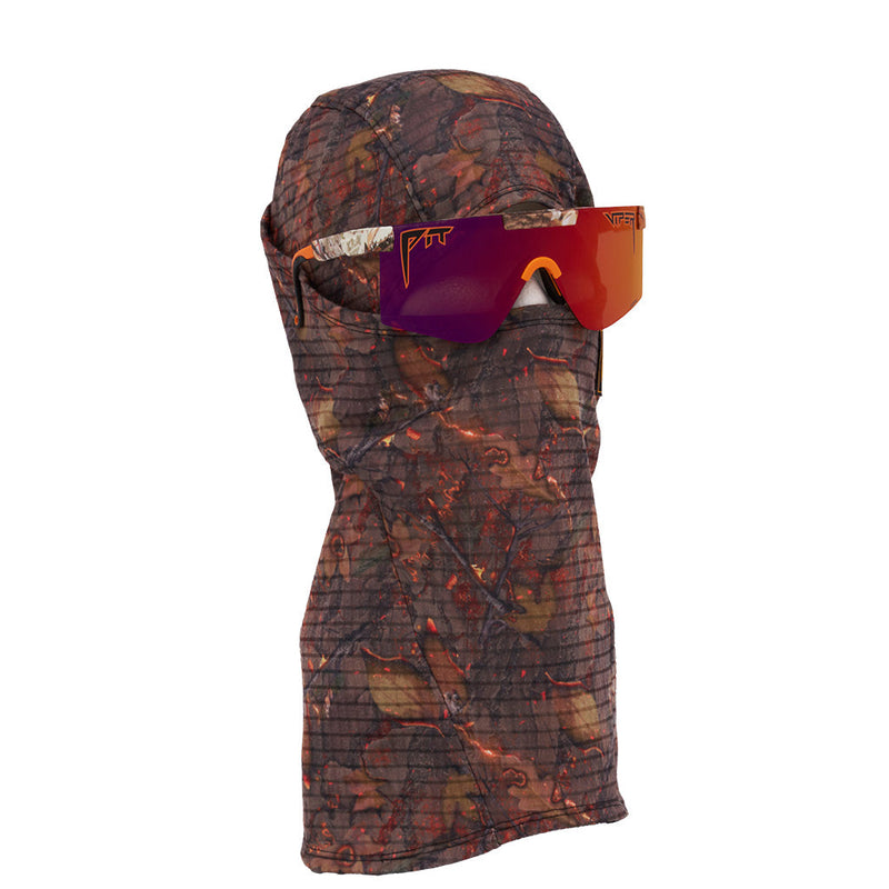 | even_more_side_view.JPG | A camouflage-print balaclava face covering with a grid texture, shown wearing reflective orange and purple goggles on a solid white background.
