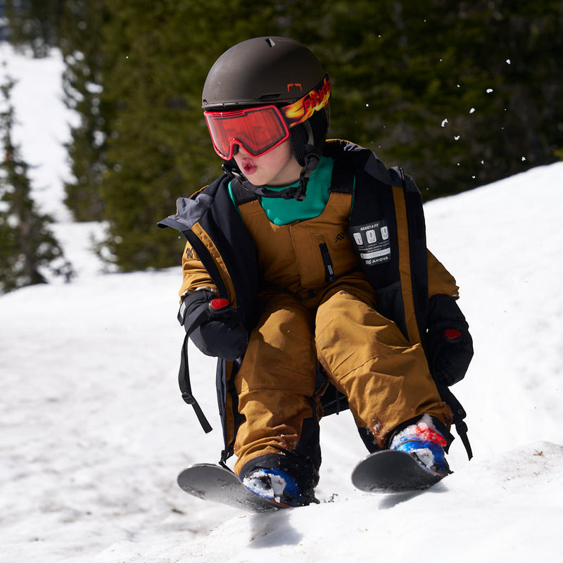 | oliver_rips_2.JPG | A child wearing a brown ski suit, black helmet, and red goggles slides down a snowy mountain slope.