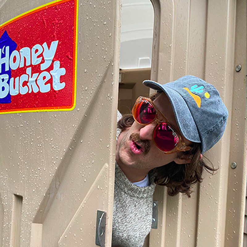  | photo_of_person.JPG | Man peaking out of a port-a-potty wearing the Courduroy Exciters from Pit Viper Sungasses