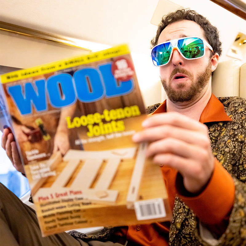 / Blue-Green | beep.JPG | A man reading a magazine on a plane wearing Pit Viper Sunglasses