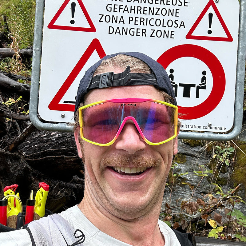  | photo_of_a_wierd_person.JPG | Man smiling in front of a sign wearing the Italo Try-Hard from Pit Viper Sunglasses