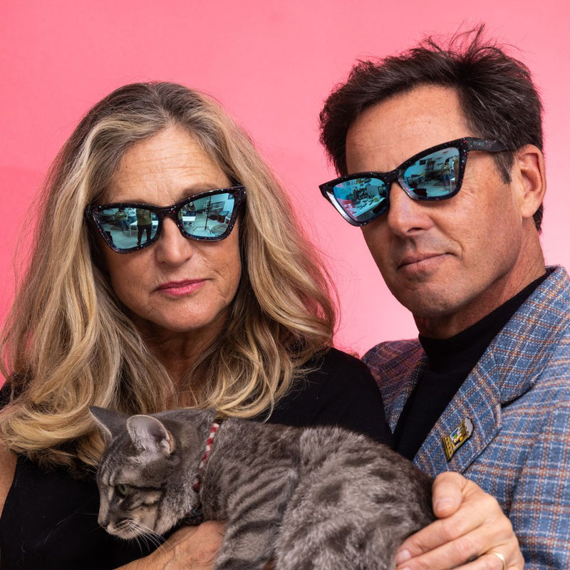 / Blue | photo_of_persons.JPG | A woman and a man wear The Midnight Clawdia with a blue lens from Pit Viper while holding a cat